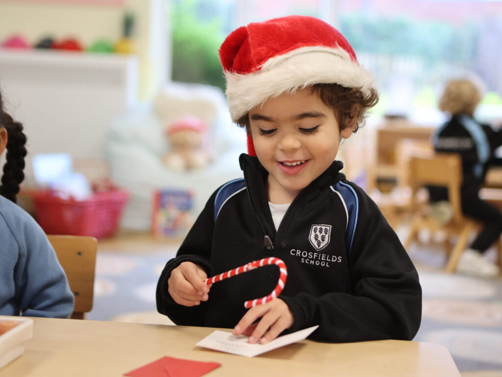 Nursery child at Crosfields School in Reading playing with Santa and a candy cane during the Christmas celebration