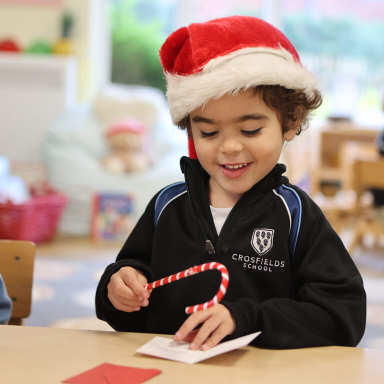 Nursery child at Crosfields School in Reading playing with Santa and a candy cane during the Christmas celebration